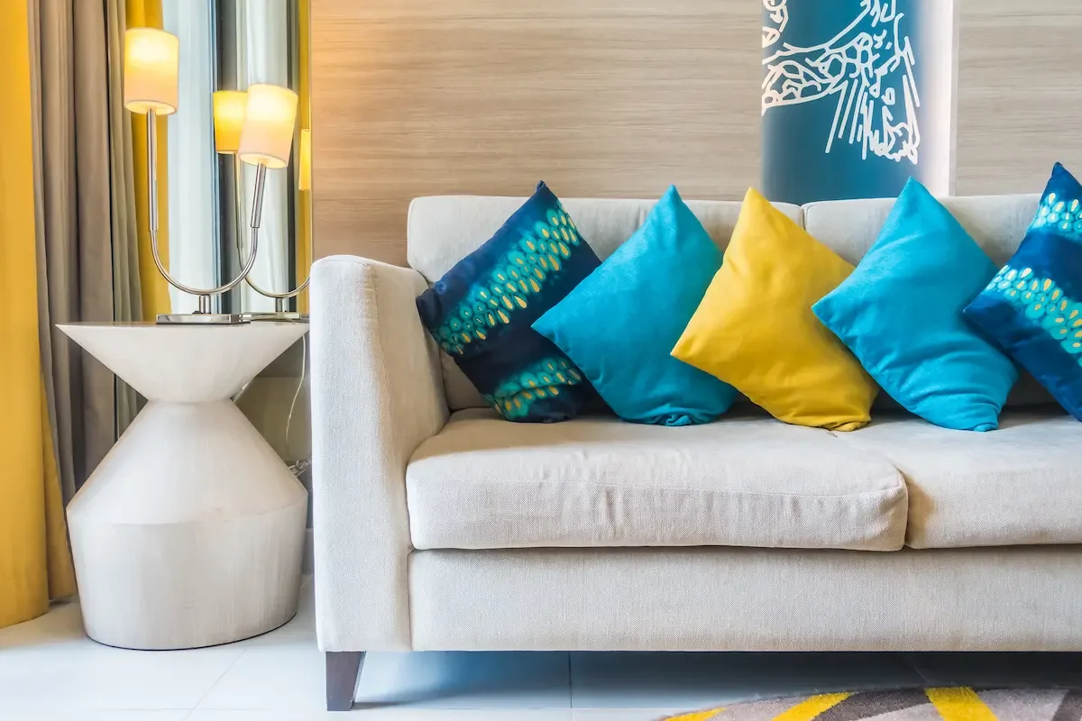 Sofá beige decorado con cojines de lino y bouclé en tonos tierra en un salón luminoso
